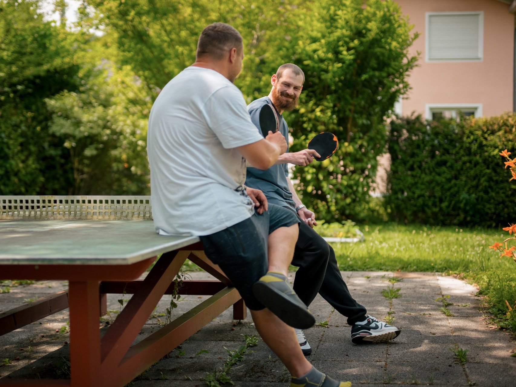 Zwei Männer sitzen auf einer Tischtennisplatte und unterhalten sich.