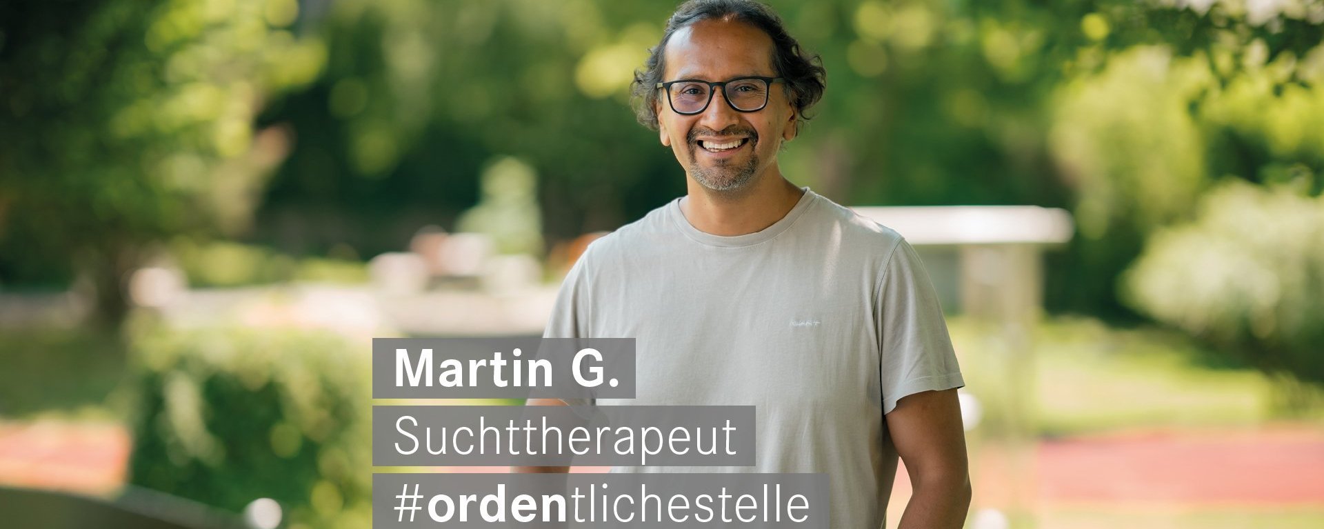 Ein Mann steht im Garten und lächelt.