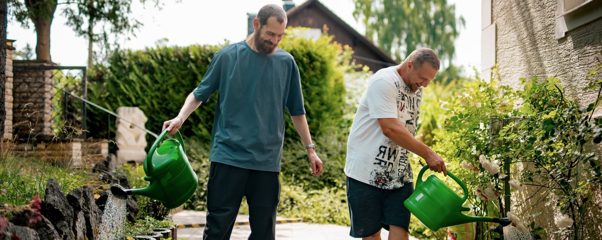 Zwei Männer gießen Blumen.