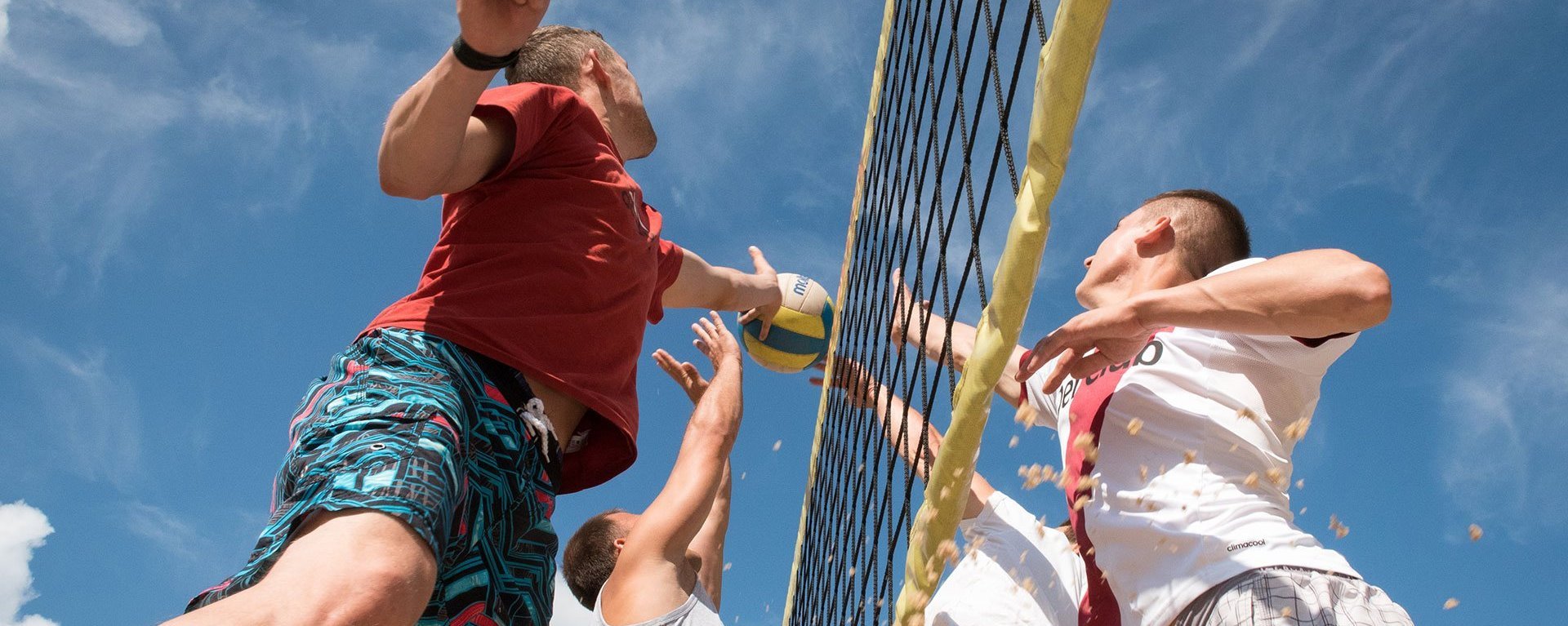 Beachvolleyball: vier Männer spielen - der Ball soll über die Netzkante aber der Block steht!