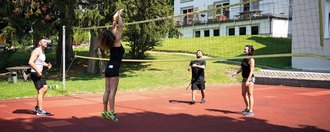 Volleyball auf dem Hartplatz: zwei gemischte-doppel-Paarungen stehen sich gegenüber und spielen